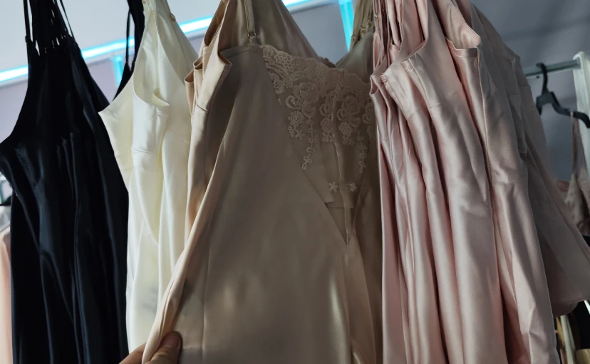 Pink silk slip dress with lace detailing hanging on display